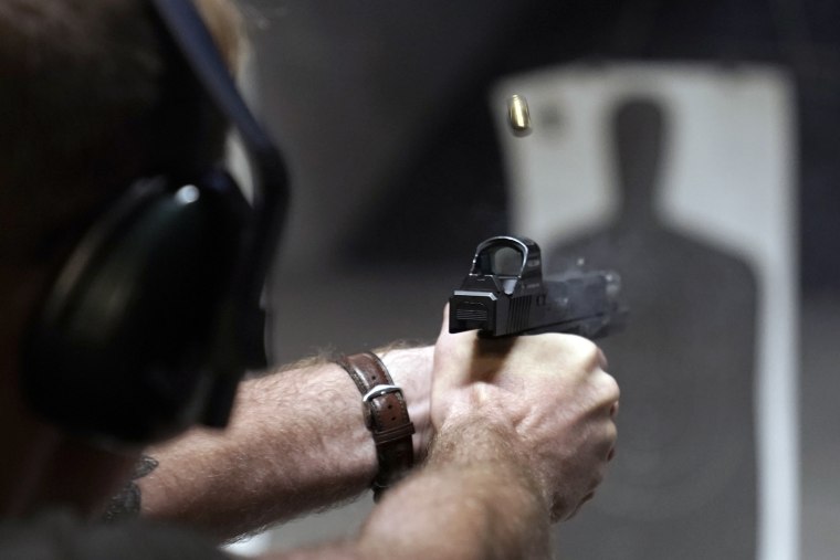 A man fires his pistol at an indoor shooting range