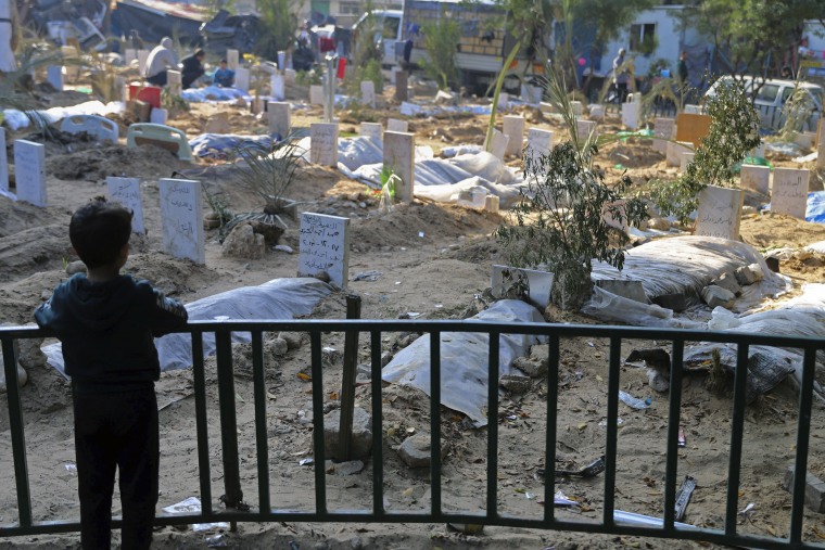 A Palestinian child looks at the graves of people killed in the Israeli bombardment of the Gaza Strip and buried inside the Shifa Hospital grounds in Gaza City on Sunday.