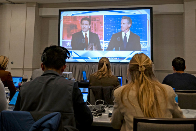 Los gobernadores Ron DeSantis, de Florida, y Gavin Newsom, de California, aparecen en un televisor en el cuarto de prensa en Alpharetta, Georgia, el 30 de noviembre de 2023. 