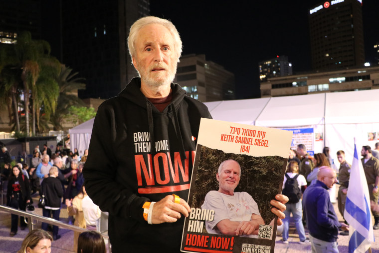 Lee Siegel stands in 'Hostage Square' in Tel Aviv holding up a sign with his brother's photo.