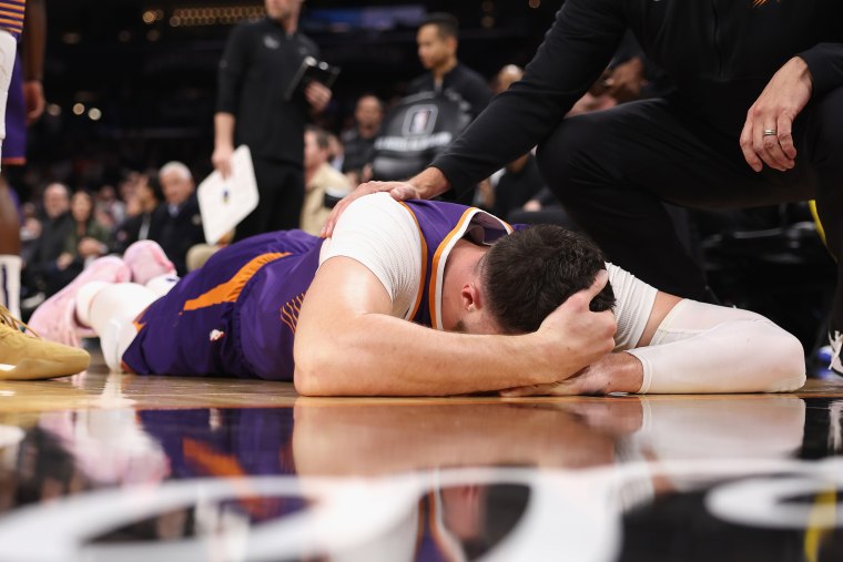 Jusuf Nurkić of the Phoenix Suns lays on the court after being fouled by Draymond Green of the Golden State Warriors during the second half of the NBA game at Footprint Center on Dec. 12, 2023 in Phoenix, Arizona. 