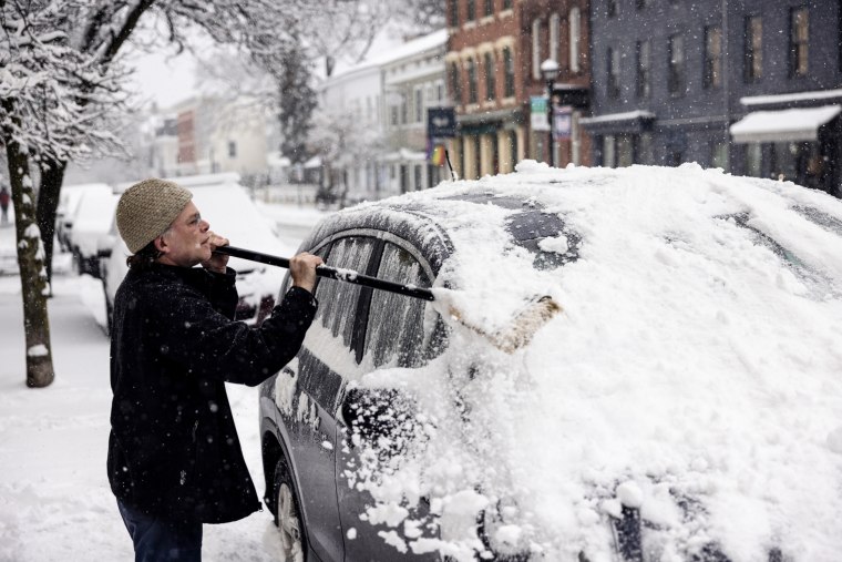A resident cleans snow off a vehicle during a storm in Hudson, New York on Jan. 7, 2024. 