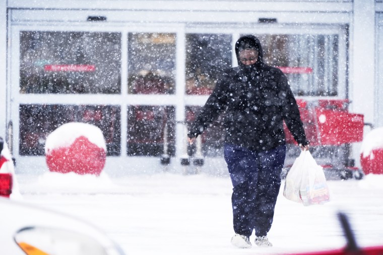 A shopper makes her way through the snow after shopping in Urbandale, Iowa on Jan. 12, 2024.