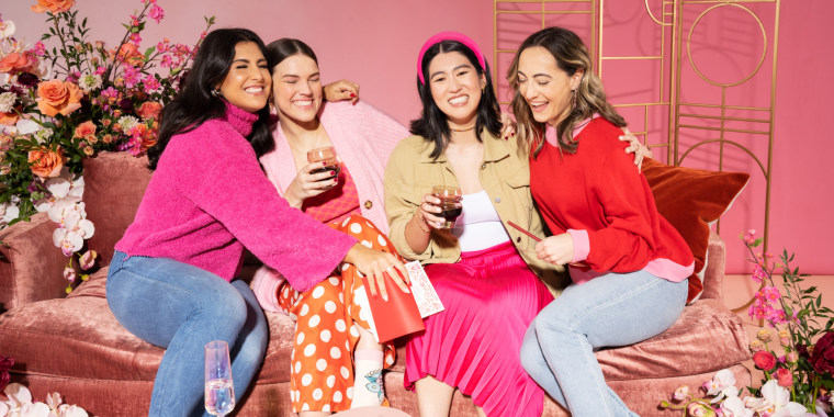 four women embracing while exchanging Galentine's day gifts.
