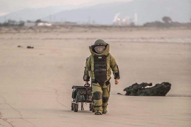 A member of the Santa Cruz Sheriff's Office bomb team removes military ordnance from the beach on Dec. 31, 2023. 