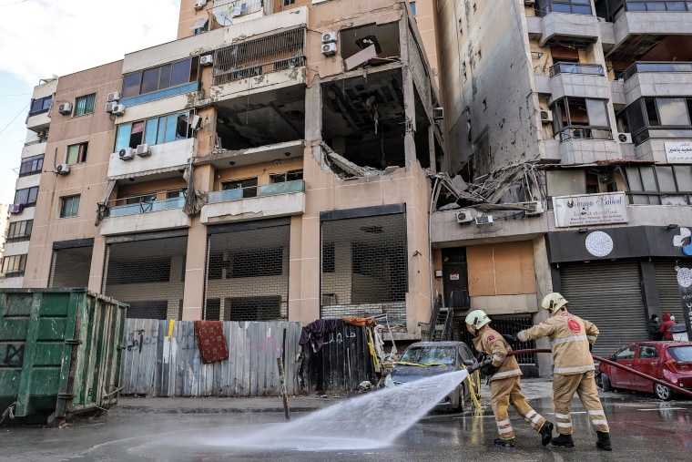 Lebanese civil defense members spray water on the street on Jan. 3, 2024, at the building that was hit the day before by a strike that killed Hamas deputy leader Saleh al-Aruri in Beirut.