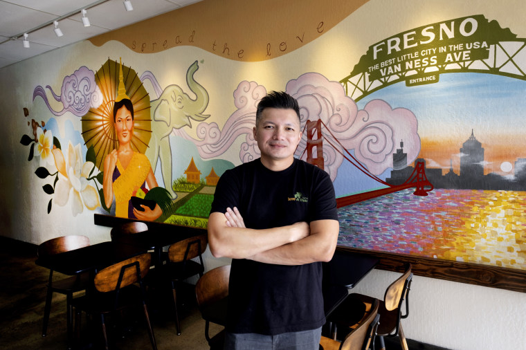 David Rasavong stands by a mural depicting his family's journey from Laos to San Francisco and then to Fresno, in his restaurant "Love & Thai" in Fresno, Calif. 