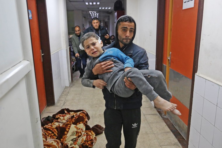 A Palestinian man carries an injured boy at Al-Aqsa Martyrs Hospital in Deir al Balah, Gaza, on Jan. 5, 2024. 