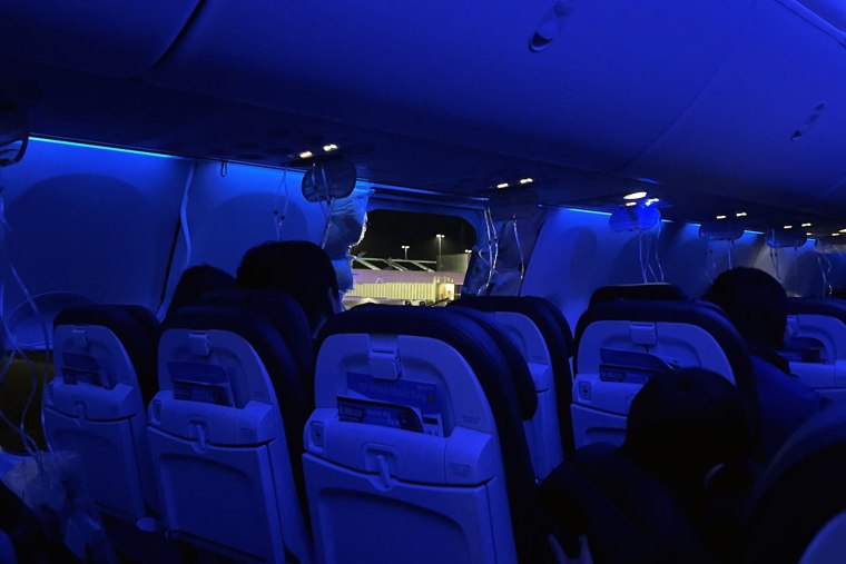 People sit on a plane next to a missing window and portion of a side wall of an Alaska Airlines Flight 1282, in Portland, Oregon