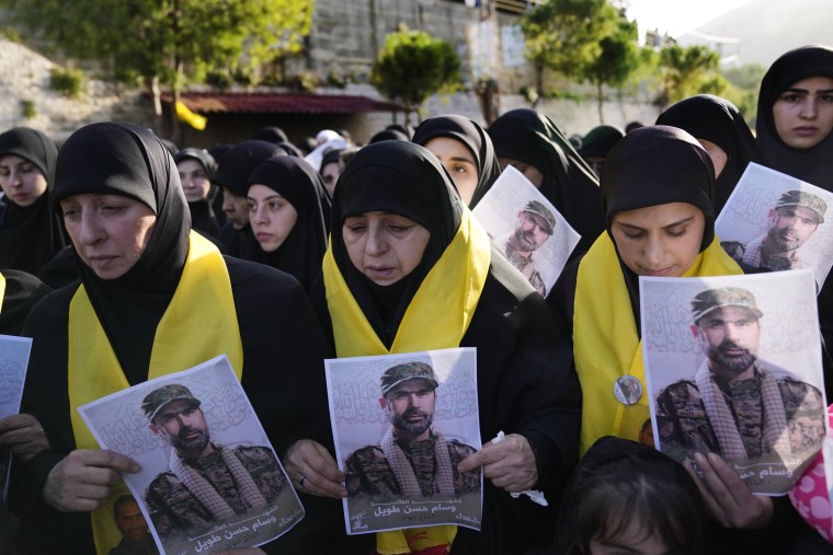 Mourners hold portraits of senior Hezbollah commander Wissam Tawil during his funeral procession in the village of Khirbet Selm, Lebanon