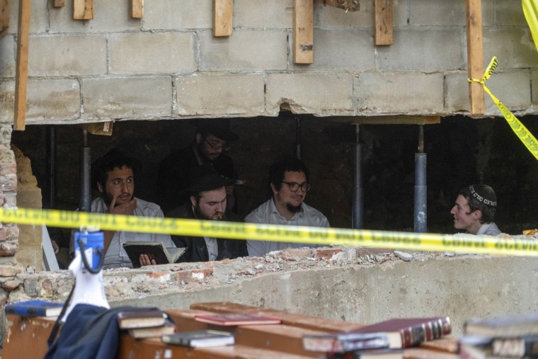 Hasidic Jewish students sit behind a breach in the wall of a Brooklyn synagogue that led to a tunnel dug by the students.