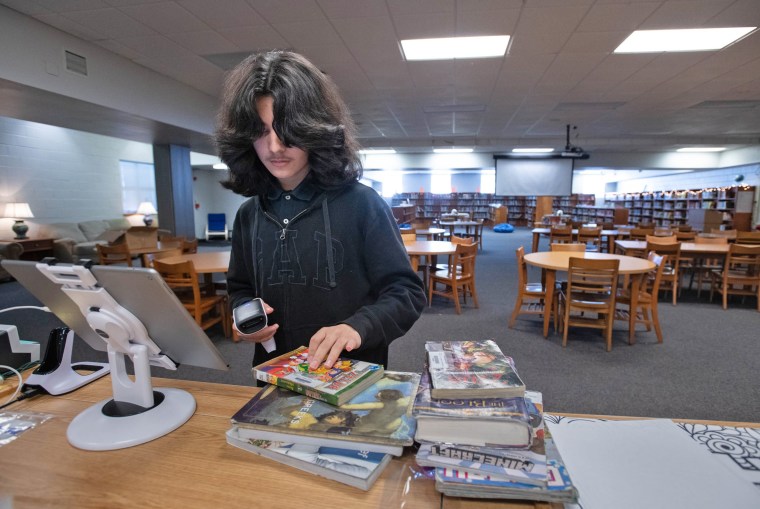 A student checks in books at Bellview Middle School in Pensacola in Florida's Escambia County on Dec. 18, 2023. 