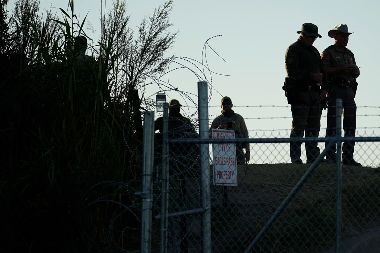 Texas troopers stand near a "No Trespassing" sign and concertina wire