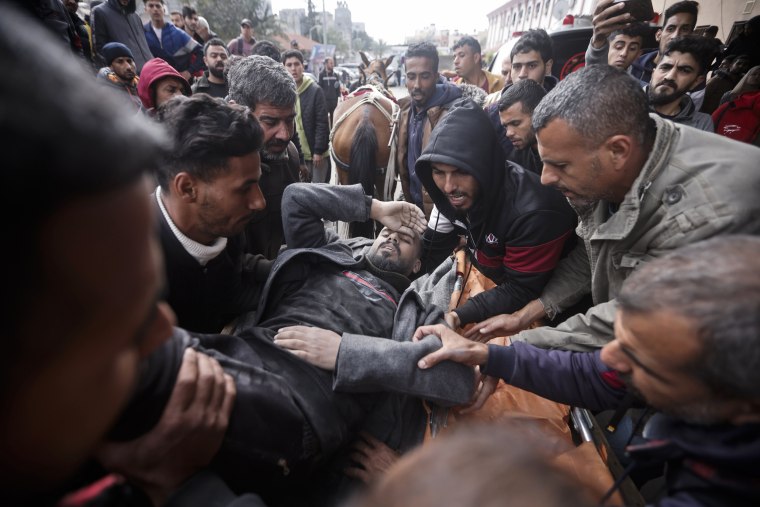 Palestinians evacuate a wounded man after an Israeli strike in Khan Younis, Gaza Strip, Friday, Jan. 12, 2024.