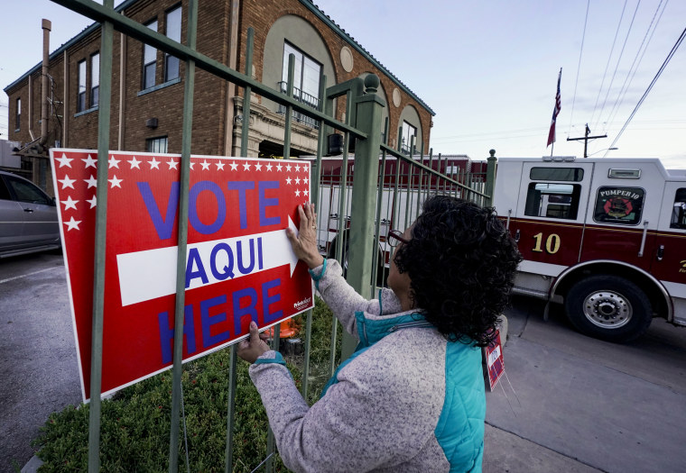 Election worker Ramona Ortiz places a sign outside a polling station 