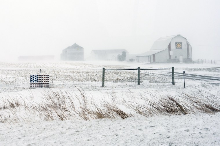 An American flag is seen fixed to a farm fence along U.S. Highway 20 during a blizzard near Galva, Iowa, on Saturday.