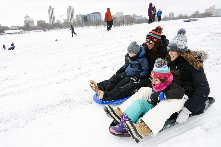 Allison Melowsky and wife Sarah Melowsky sled down Cricket Hill on Saturday with their kids Parker, 7, and Zane, 4, after a snowstorm hit the Chicago area.
