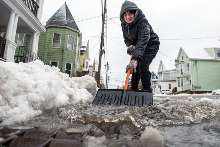 Amber Vallee pushes water down Walnut Street in Lewiston, Maine, on Saturday morning, after snow turned to rain during yet another storm of mixed precipitation hit the area. 