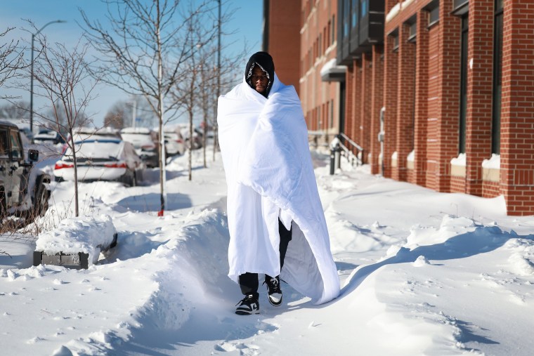 Diamani Glo bundles up in a blanket as he walks in -12 degree weather on Jan. 14, 2024, in Des Moines, Iowa. 