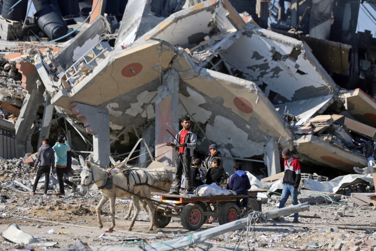 A donkey cart drives past a collapsed building in the Al-Maghazi refugee camp in central Gaza Strip, on Jan. 16, 2024.