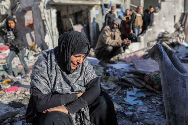 A woman sits amongst damaged homes caused by Israeli air strikes in Rafah, Gaza