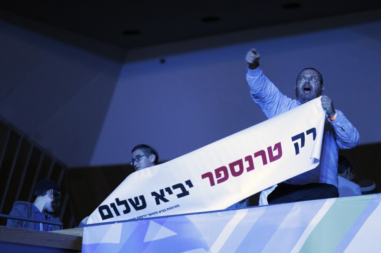 A man holds a billboard that says "only transfer to Palestinians will bring a peace" in Jerusalem on Sunday.