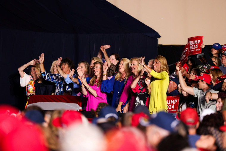 Women wave at a Trump campaign rally.
