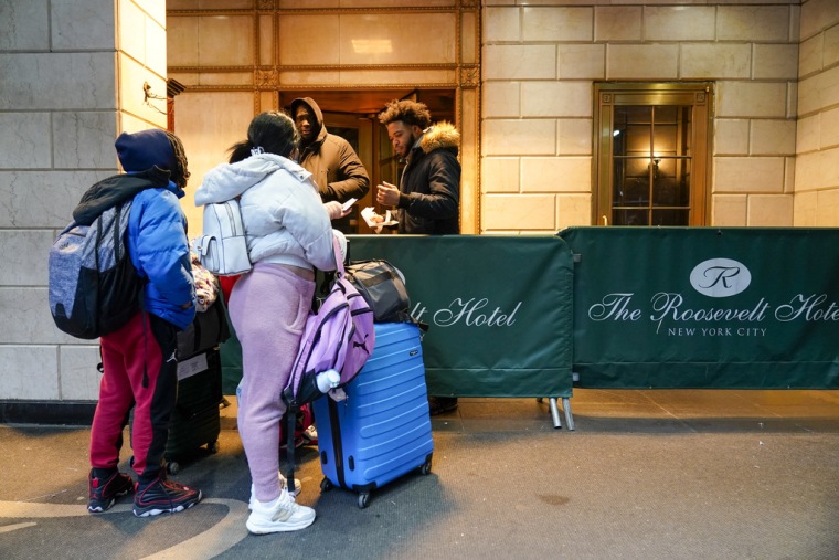 Una familia de migrantes muestra su documentación a los guardias de seguridad en el Hotel Roosevelt, el martes 9 de enero de 2024, en la ciudad de Nueva York. (AP Foto/Mary Altaffer)
