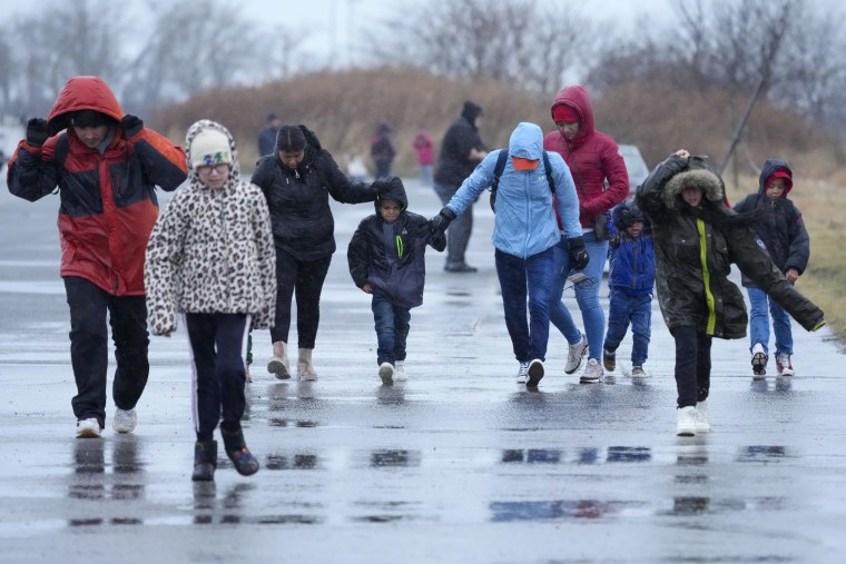 Migrantes caminan bajo la lluvia en el Floyd Bennett Field, en Brooklyn, Nueva York, el martes 9 de enero de 2024.