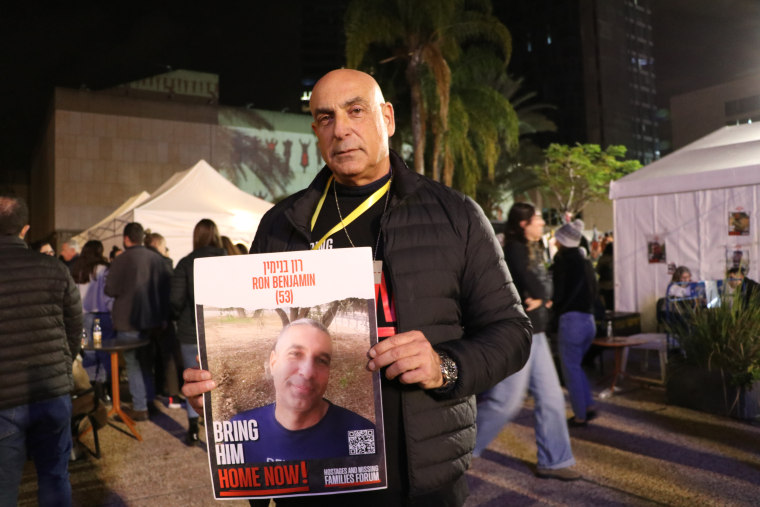 Shuki Benjamin holds up a poster of his brother, Ron Benjamin, 53, who was taken hostage by Hamas while trying to return home from a cycling trip.