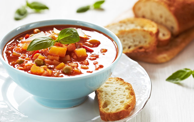 Bowl of minestrone soup with a slice of bread on the side