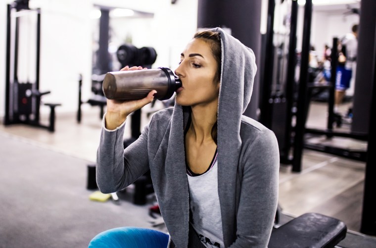 Woman bodybuilder drinking protein shake at gym