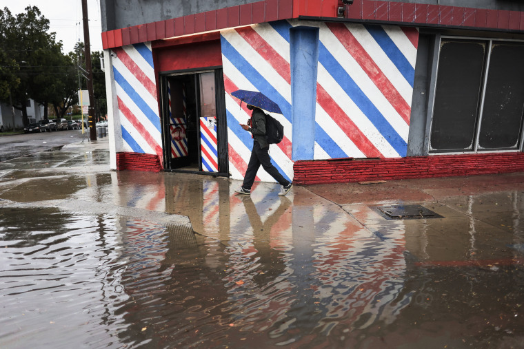 A man walks by a flooded road during a rain storm in Long Beach, Calif. on Feb. 1, 2024.
