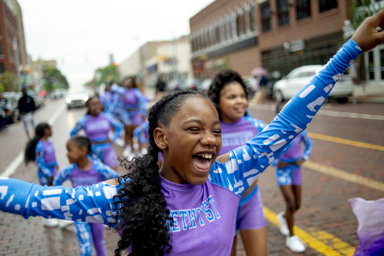 Lexi Watson, 10, of Flint, smiles as she shouts out with joy with Amethyst, an elite dance company, while marching in one of two Juneteenth parades along Saginaw Street in downtown Flint, Mich., Saturday, June 19, 2021.