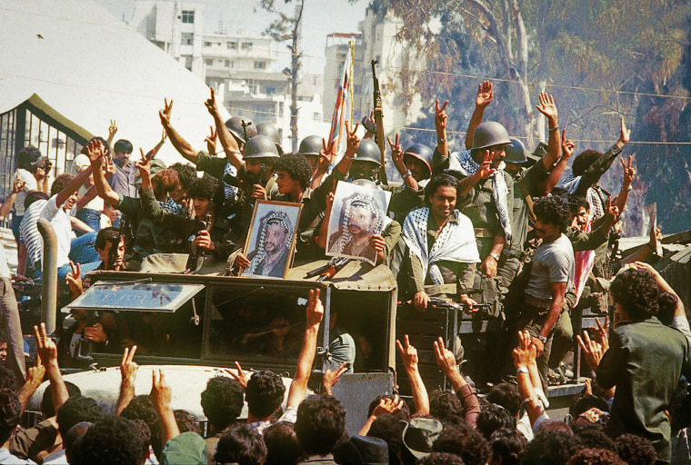 Palestinian fighters hold portraits of Yasser Arafat, chairman of the the Palestine Liberation Organization, on Aug. 22, 1982, as they leave Israeli-occupied Beirut for Tunis.