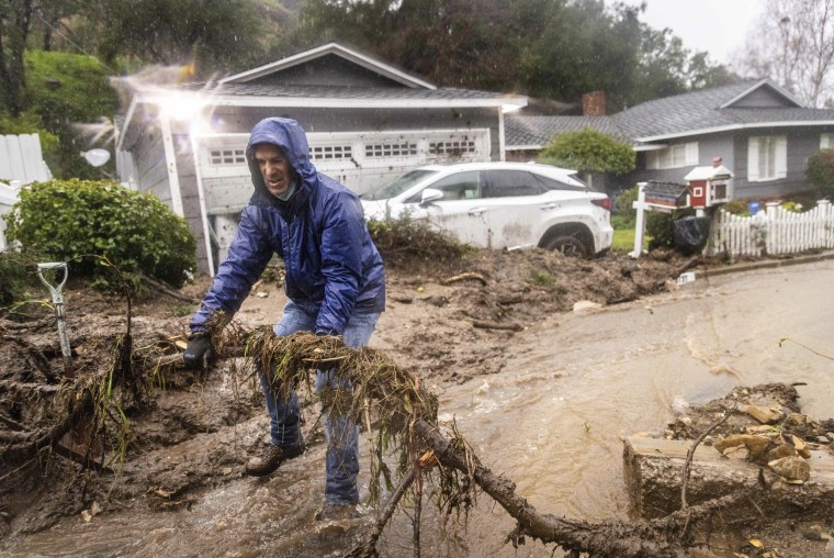 Jeffrey Raines clears debris from a mudslide at his parent's home during a rainstorm, Monday, Feb. 5, 2024, in Los Angeles. 