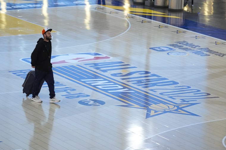 Travelers using Indianapolis International Airport make their way across a replica of the court that will be use for the NBA All-Star game