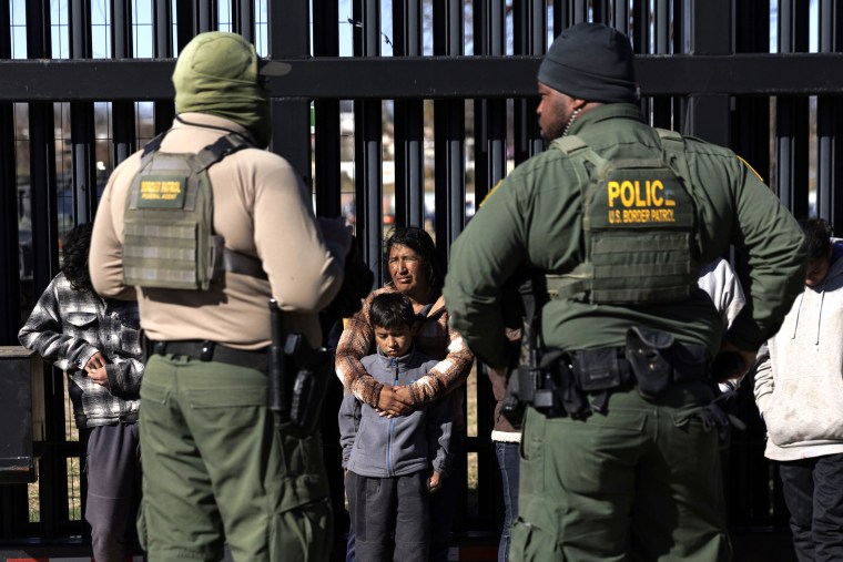 U.S. Border Patrol agents guard migrants that crossed into Shelby Park as they wait to be picked up for processing in Eagle Pass, Texas