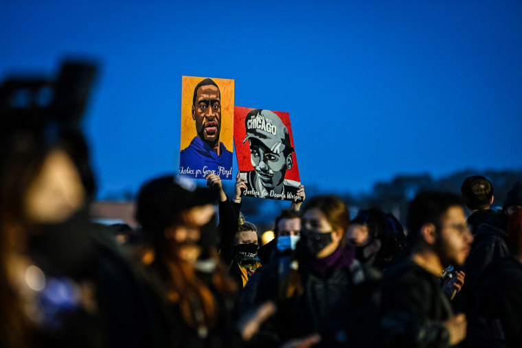 Demonstrators hold George Floyd and Daunte Wright's portraits during protests over the shooting death of Daunte Wright by a police officer in Brooklyn Center, Minn., on April 16, 2021.