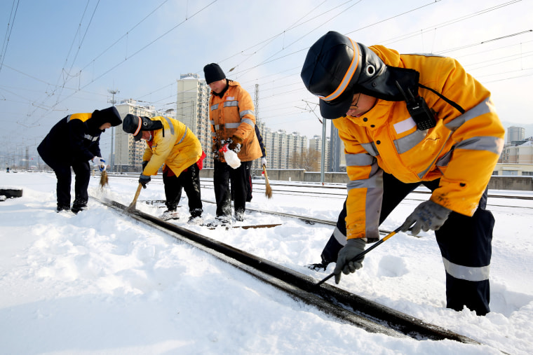 Workers clear ice and snow off the tracks along Lianyungang East railway station