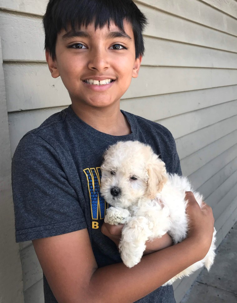 Childhood photo of Akul Dhawan smiling while holding a puppy.