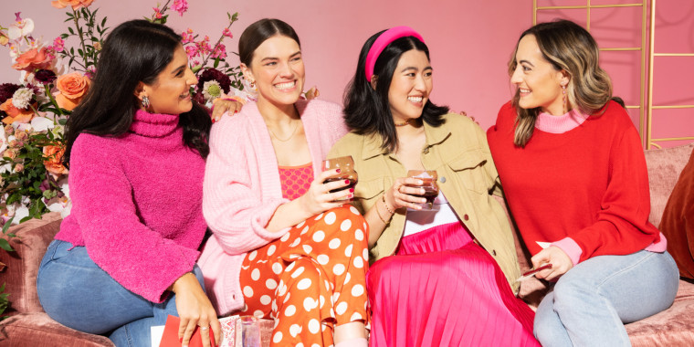 Four women in valentine's day outfits laughing and enjoying each other's company.