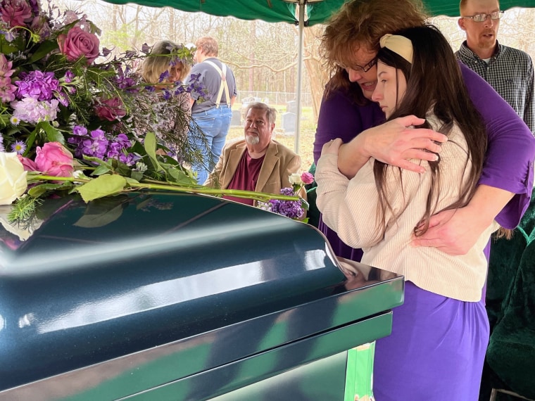 Gretchen hugs Jonathan's daughter, Brooke, and places flowers on his coffin.