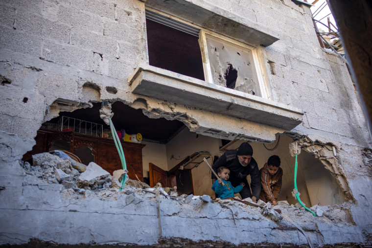 Palestinians look at the destruction after an Israeli strike .