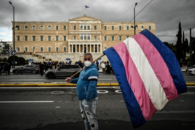 Image: A person holds a transgender flag outside the Greek Parliament 