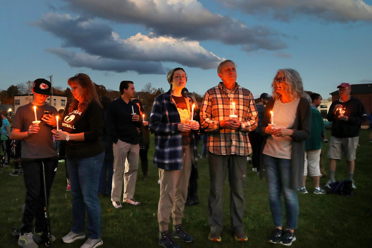 People hold candles during acandlelight vigil.