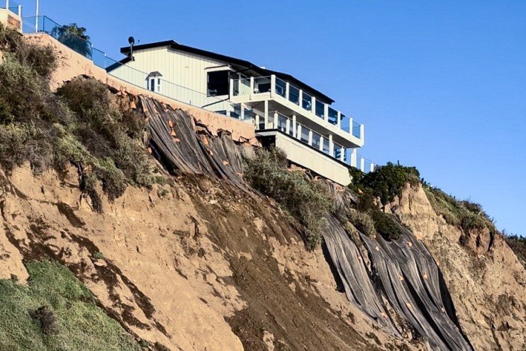 Tarps cover the bluff behind a home looking over Capistrano Beach in Dana Point, Calif. Several seaside neighborhoods are dealing landslides and concerns of coastal erosion following lates round of storms hitting the state.