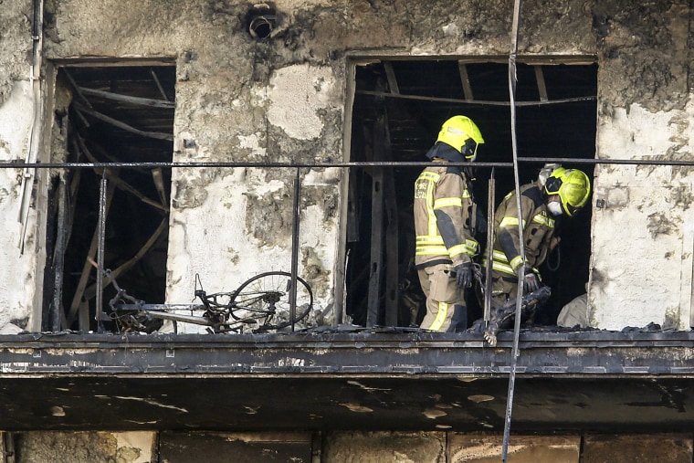 Image: Firefighters remove a charred body inside a burned block building in Valencia, Spain