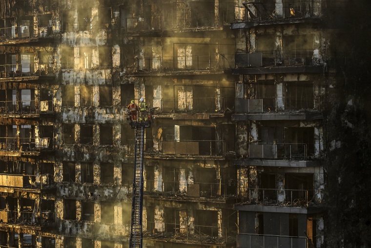Image: Firefighters work at a burned block building in Valencia, Spain