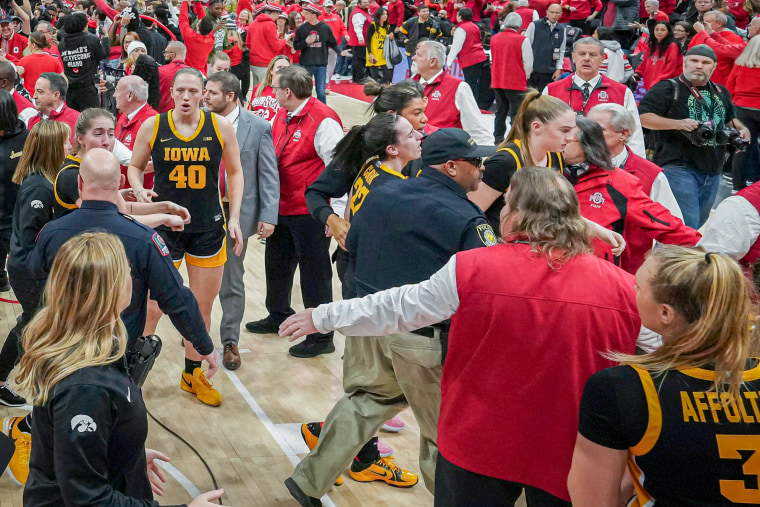 Iowa guard Caitlin Clark is helped off by security as fans storm the court following Ohio State's defeat of the Hawkeyes at Value City Arena.